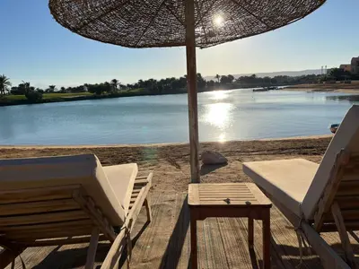 a couple of chairs and an umbrella on a beach at The Sunset Heaven - 2 bedrooms - Golf Steigenberger, El Gouna in Hurghada