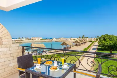 a balcony with a table and chairs with a view of the water at Aladdin Beach Resort in Hurghada