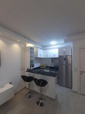 a kitchen with two bar stools and a refrigerator at SKY EL Gandoul Wohnung Hurghada in Hurghada