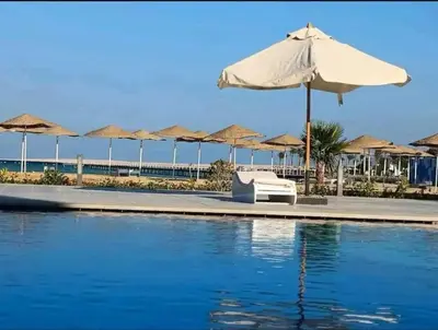 a pool with an umbrella and chairs and umbrellas at Scandic sea view in Hurghada