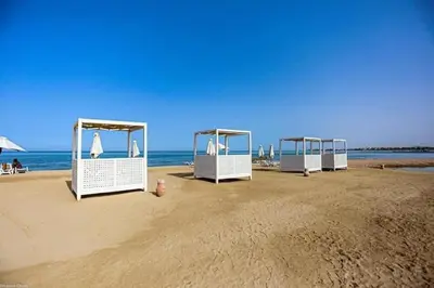 a row of white shelters on a beach at Chic 3BR Ground Free Beach & Pool access at Mangroovy in Hurghada