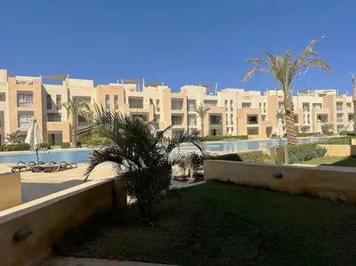 a view of a large building with palm trees and a pool at Chic 3BR Ground Free Beach & Pool access at Mangroovy in Hurghada