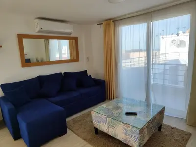 a living room with a blue couch and a glass table at Stunning Rooftop 1 Bed Apartment in Hurghada