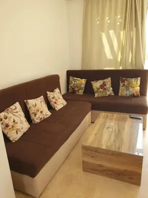 a brown couch with pillows and a coffee table in a living room at Serene Pool View 8Mins to Marina in Hurghada