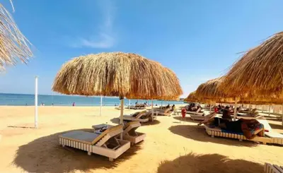 a group of beach chairs and straw umbrellas on a beach at Princess resort luxury A109 in Hurghada