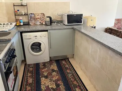 a kitchen with a washing machine and a counter at Lovely flat with balcony and shared pool in Hurghada