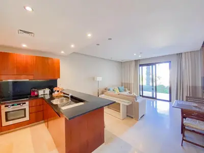 a kitchen with a sink and a living room at Nayah Stays, Ancient Sands Luxurious Pool Terrace Apartment in Hurghada