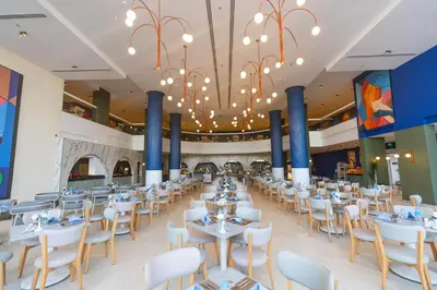 a dining hall with tables and chairs and a chandelier at Flow Spectrum Resort Sahl Hasheesh in Hurghada