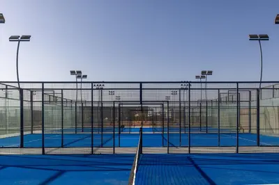 a tennis court with a fence and some lights at Aldiana Club Naga Bay in Hurghada