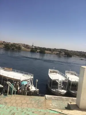two boats are docked on a river with a car at بيت ملكه house of malaka in Naj‘ al Maḩaţţah