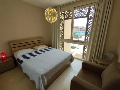 a bedroom with a bed and a couch and a window at SunShine Mangrove in Hurghada