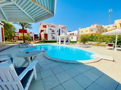 a swimming pool in a resort with chairs and an umbrella at hurgada hapy room in Hurghada