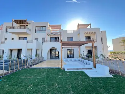 a large white house with a yard in front of it at Stylish 1BR Ground With Free Pool & Lagoon Access In Gouna in Hurghada