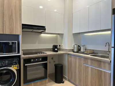a kitchen with white cabinets and a washer and dryer at Stylish 1BR Ground With Free Pool & Lagoon Access In Gouna in Hurghada