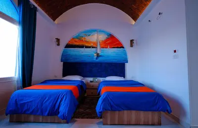 two beds in a room with a painting on the wall at JAREEDY Guest house in Shellal