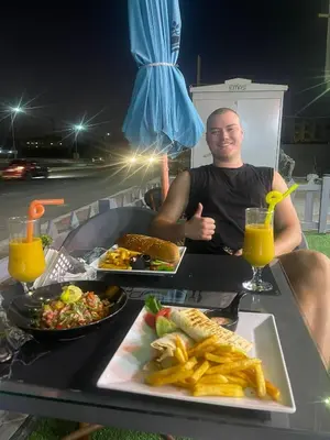 a man sitting at a table with plates of food at Hotel apartment with a private beach in Hurghada