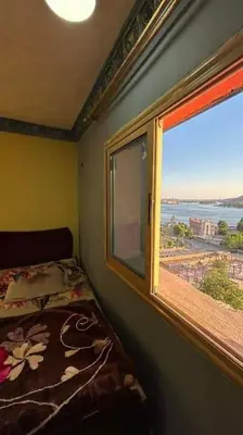 a bedroom with a window and a bed with a view at The best view of the Nile in Naj‘ al ‘Amrāb