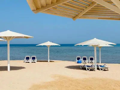 a group of chairs and umbrellas on a beach at Colin beach in Hurghada