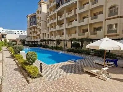 a swimming pool in front of a large building at Florenza khamsin Apartment in Hurghada