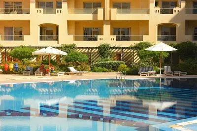 a swimming pool in front of a building with umbrellas at Florenza khamsin Apartment in Hurghada