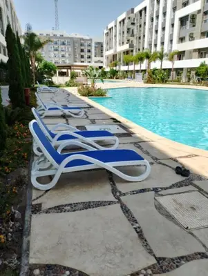 a row of lounge chairs next to a swimming pool at Red Sea Hurghada Summer in Winter in Hurghada