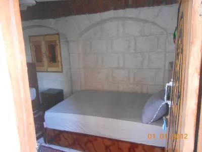 a bedroom with a bed in a stone wall at Hashem Nubian Guest House in Aswan