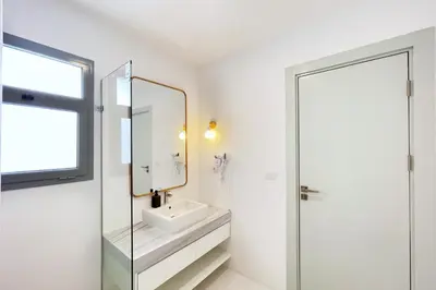 a white bathroom with a sink and a mirror at Lofty & Lavish 3 BDR Swan Lake El Gouna in Hurghada