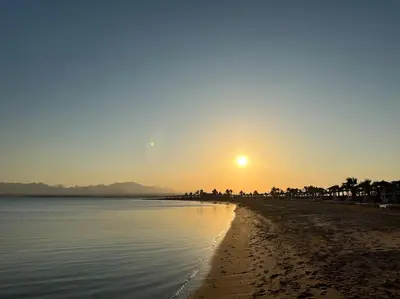 a beach with the sun setting in the distance at Somabay Seaview 1BR Loft 2 Mins to Beach & Pool in Hurghada