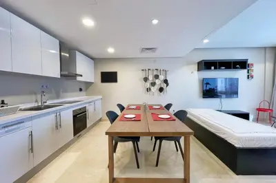 a kitchen and dining room with a table and a bed at Minimal & Mere 1 BDR Mangroovy Free Beach & Pool in Hurghada