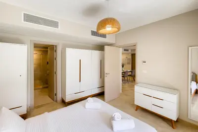 a bedroom with two white beds and a bathroom at Scenic Pool Front 1 BDR Mangroovy Free Pool & Beach in Hurghada