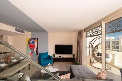 a living room with a couch and a tv at Vogue & Idyllic 2 BDR Mangroovy Free Pool & Beach Access in Hurghada