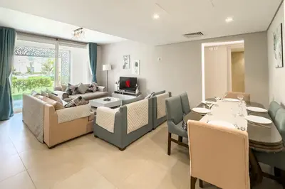 a living room with a couch and a table and chairs at Staggering & Soothing 2 BDR w Pool View Free Pool & Beach Access in Hurghada