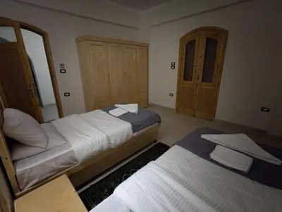 a bedroom with two beds and a cabinet at Pharaohs Apartments in Luxor