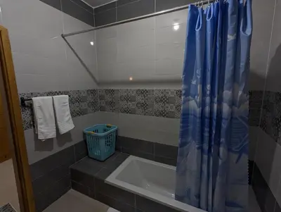 a bathroom with a tub and a blue shower curtain at Pharaohs Apartments in Luxor