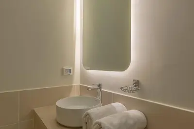 a white bathroom with a sink and a mirror at Comfy 2BR in Shedwan El Gouna Garden BBQ, Pool, Lagoon in Hurghada