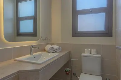 a bathroom with a toilet and a sink and two mirrors at Comfy 2BR in Shedwan El Gouna Garden BBQ, Pool, Lagoon in Hurghada