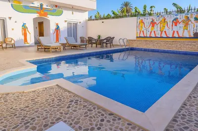 a swimming pool with blue water in front of a building at LUXOR DREAM - Panoramic Villa in Luxor