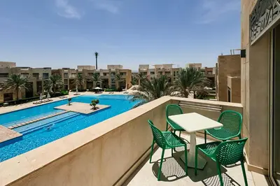 a balcony with a table and chairs and a swimming pool at Stellar 1BDR Mangroovy Free Pool & Beach Access in Hurghada