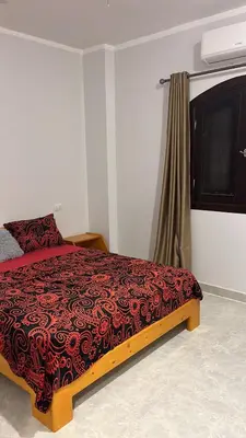 a bedroom with a bed with a red and black blanket at Villa Muhammad in Quseir