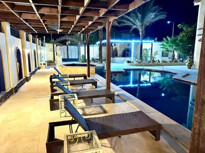 a swimming pool with chairs and a table next to a house at Private villa in Hurghada in Hurghada