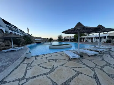 a swimming pool with chairs and umbrellas in a resort at Mastaba Village Hurgada House in Hurghada