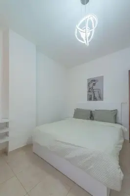 a white bedroom with a bed and a chandelier at Luxury apartment on the pool in Hurghada