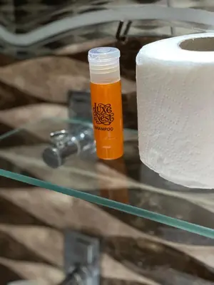 a glass table with a bottle of beer next to a roll of toilet paper at Luxe Nest Luxor Serviced Apartments 101 in Luxor