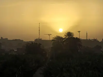 a sunset over a city with palm trees and buildings at Nanis Guest House Nile View in Luxor