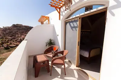 a balcony with two chairs and a bed on a house at Aro Kato Nubian Guest House in Aswan