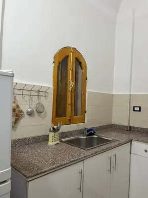 a kitchen counter with a sink and a wooden cabinet at Shamandy house same same but different in Jazīrat Aswān