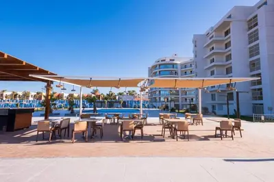 a patio with tables and chairs and a large umbrella at Scandic Resort Hurghada Red Sea in Hurghada