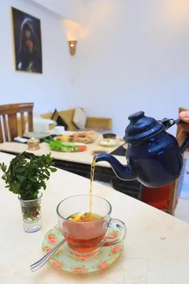 a teapot pouring tea into a cup on a table at Moka Gust House in Luxor