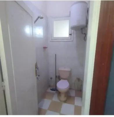 a small bathroom with a toilet and a window at Ali Toot in Luxor