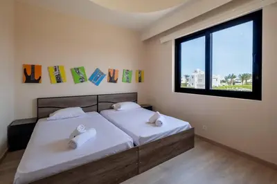 a bedroom with two beds with white sheets and a window at Luxury 4BR + Nanny Villa • Ancient Sands in Hurghada
